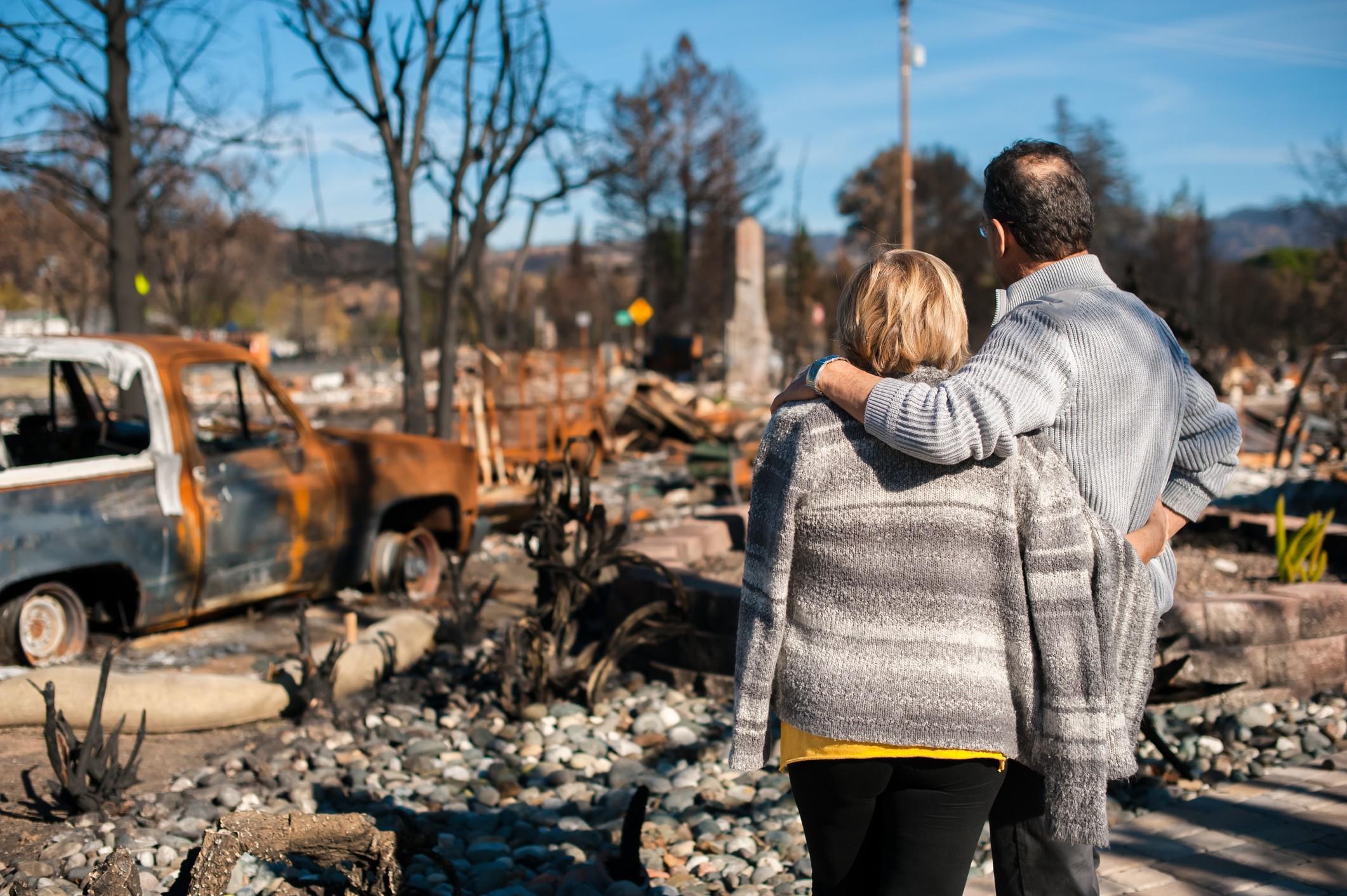 A couple surveys a burned down neighborhood